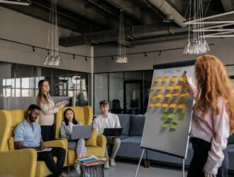 photo of a woman pointing at a whiteboard with sticky notes